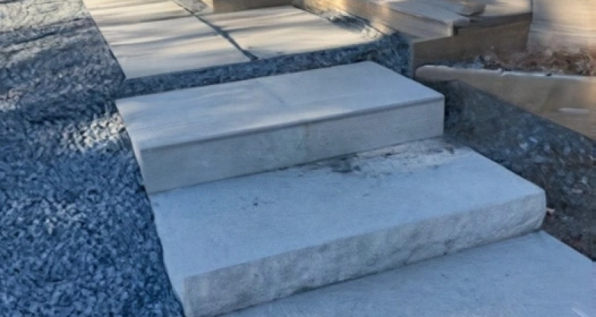 Charming antique granite steps leading through a picturesque walkway in Truro, Massachusetts, bordered by vibrant flowers and lush greenery.