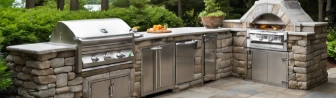 Elegant outdoor kitchen with bluestone pavers on the patio, featuring a built-in grill, stone countertops, and a stylish seating area.