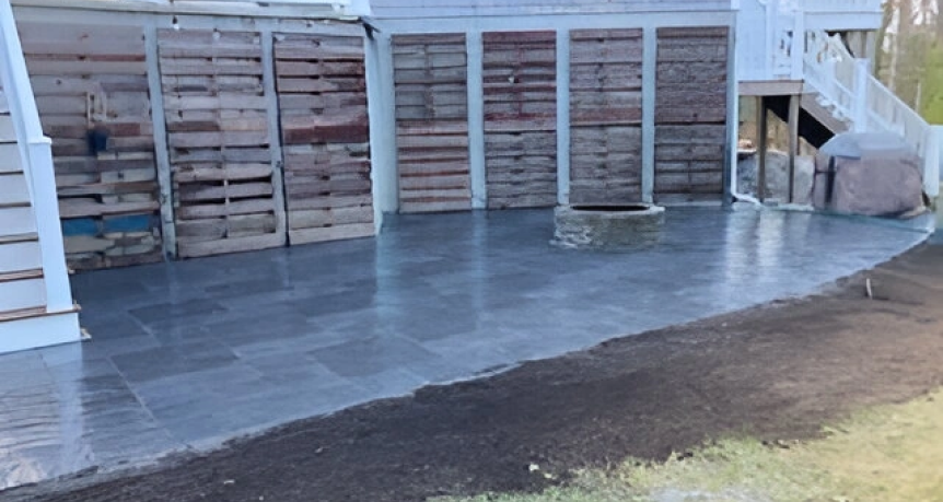Stunning Nantucket paver patio at a charming house in Yarmouth, Massachusetts, featuring intricate patterns, surrounded by lush greenery and complemented by cozy outdoor furniture.
